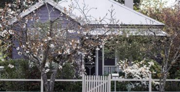White roofed home with flowering trees in the foreground